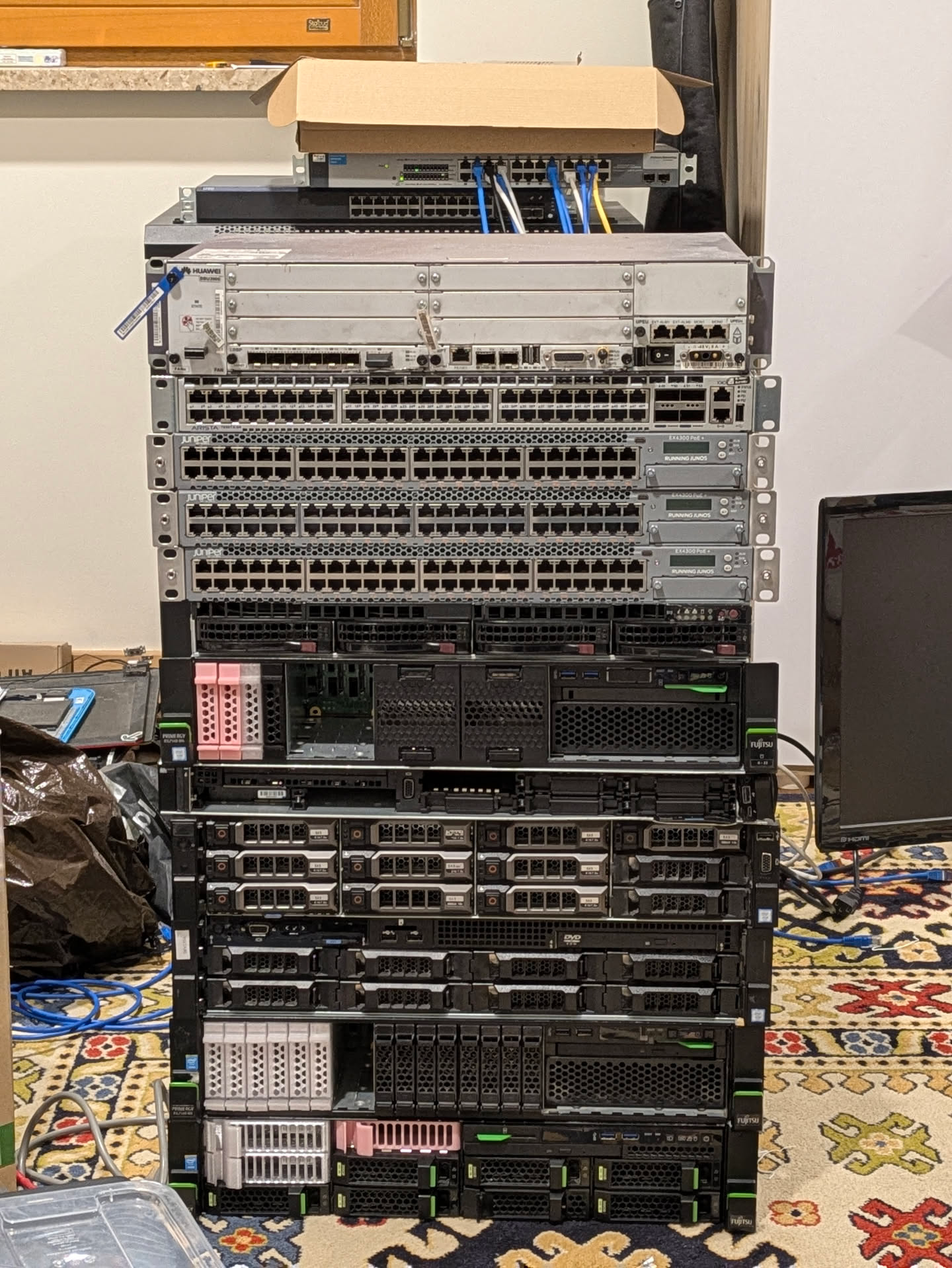 a stack of server hardware (top to bottom):
- Huawei BBU3900
- Arista DCS-7050TX
- 3x Juniper EX4300-48P
- Supermicro x11ddw-l
- Fujitsu RX2540 M5
- Dell R640
- Dell R730xd
- Dell R730
- Fujitsu RX2540 M1
- Fujitsu RX2540 M4
also a Procurve 1800-24G and an EX2200-24P in the background just above the main stack a stack of server hardware (top to bottom):
- Huawei BBU3900
- Arista DCS-7050TX
- 3x Juniper EX4300-48P
- Supermicro x11ddw-l
- Fujitsu RX2540 M5
- Dell R640
- Dell R730xd
- Dell R730
- Fujitsu RX2540 M1
- Fujitsu RX2540 M4
also a Procurve 1800-24G and an EX2200-24P in the background just above the main stack